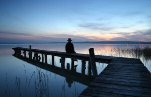 Wounded Healer sits alone on a lake